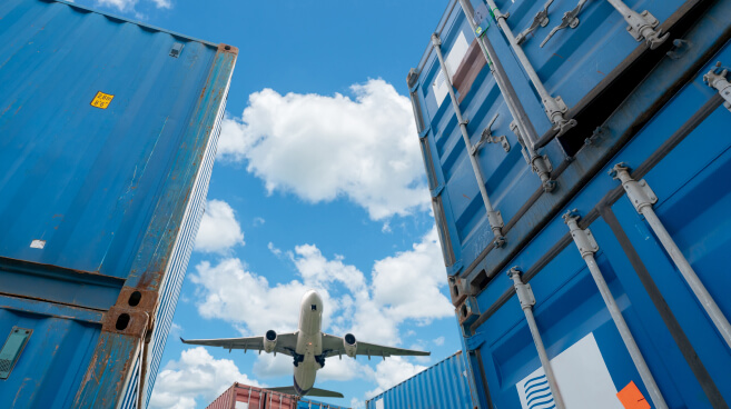 Airplane Flying Above Logistic Containers